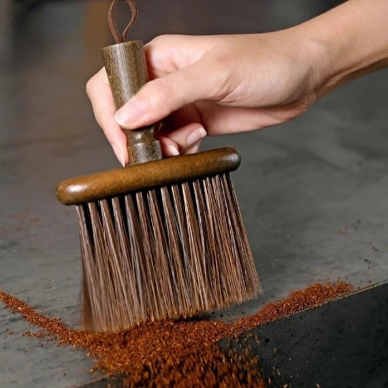 Hand holding a wooden brush over a surface with rust stains