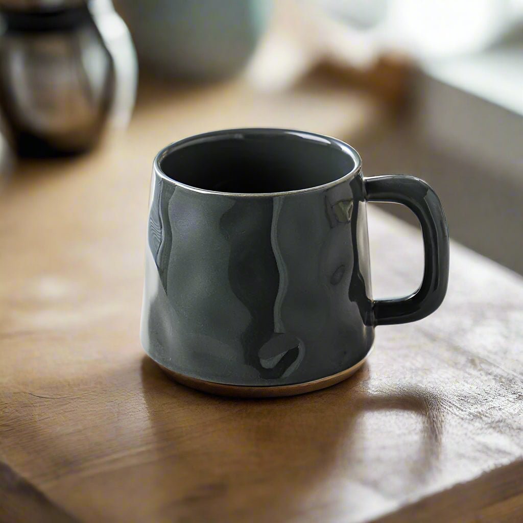 Black ceramic mug on a wooden surface with a blurred background