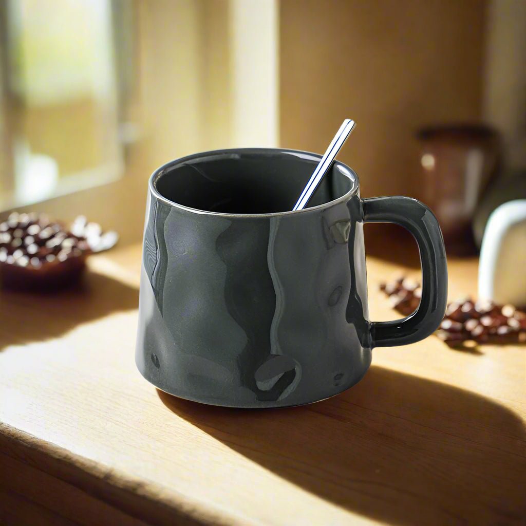 Black mug with a spoon on a wooden surface with coffee beans around