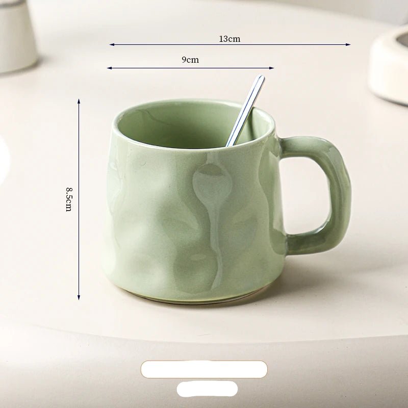 Green ceramic mug with a spoon inside, shown with dimensions on a light background