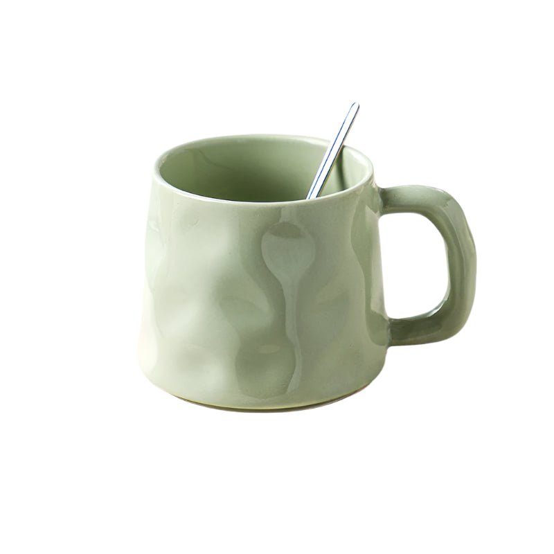 Green mug with a spoon inside on a white background