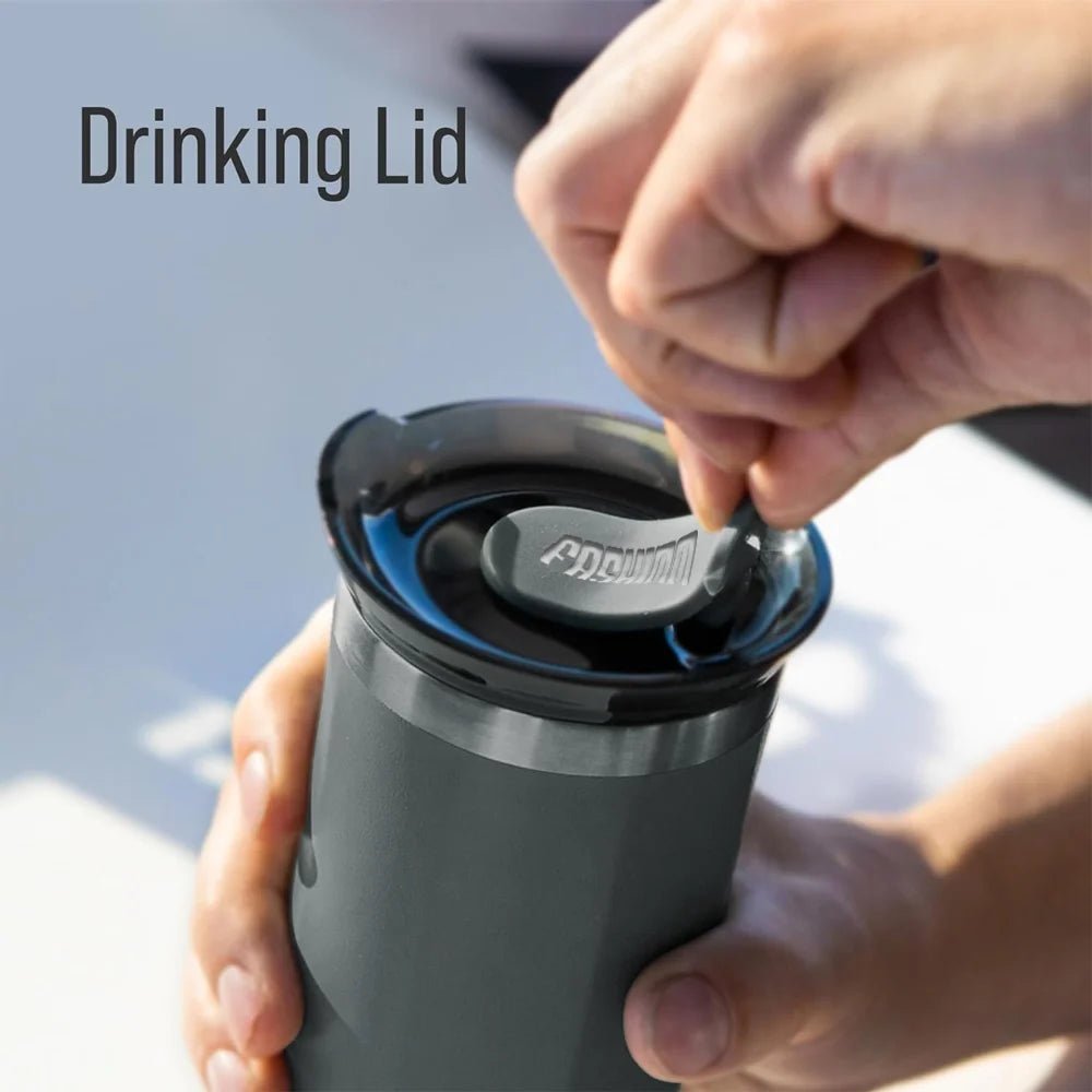 Person holding a tumbler with a drinking lid being placed on it, against a blurred outdoor background.