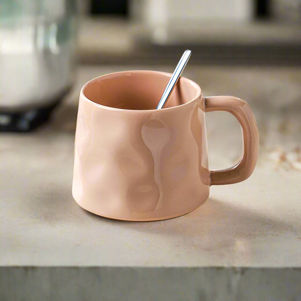 Pink mug with a spoon on a kitchen counter