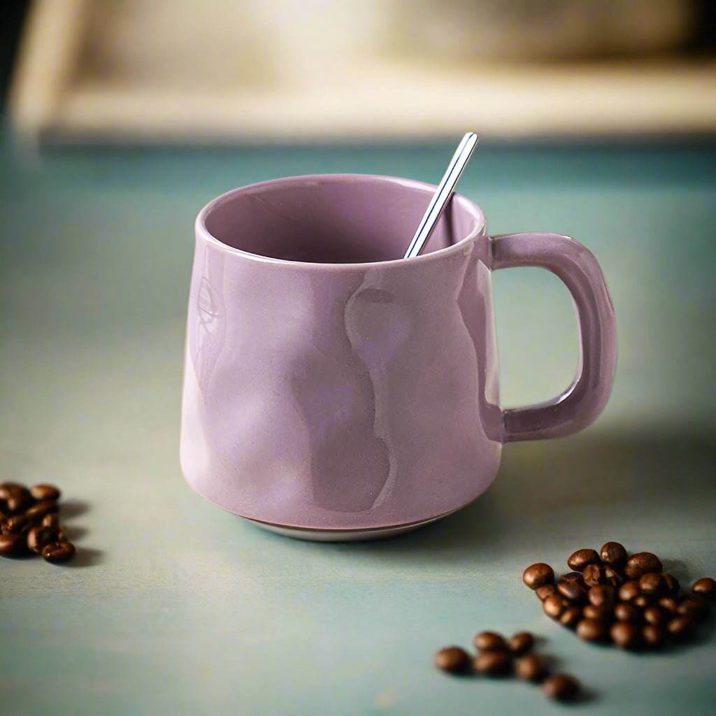 Purple mug with a spoon and coffee beans on a green surface