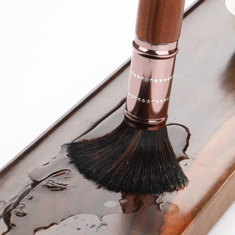 Makeup brush with rose gold handle on a reflective surface