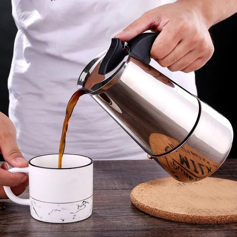 Person pouring coffee from a French press into a white mug on a wooden surface.