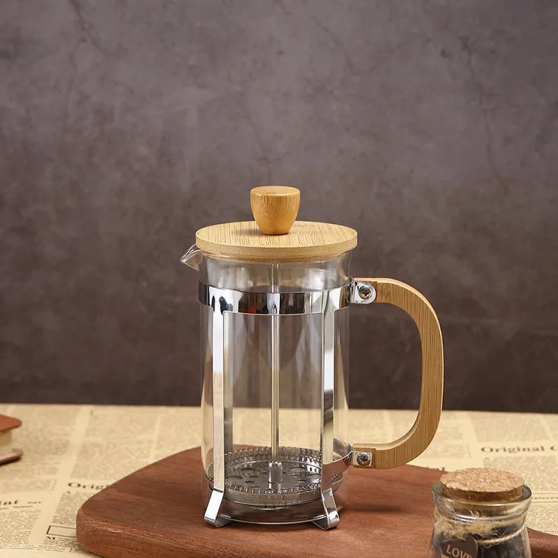 French press coffee maker with wooden lid and handle on a wooden surface.