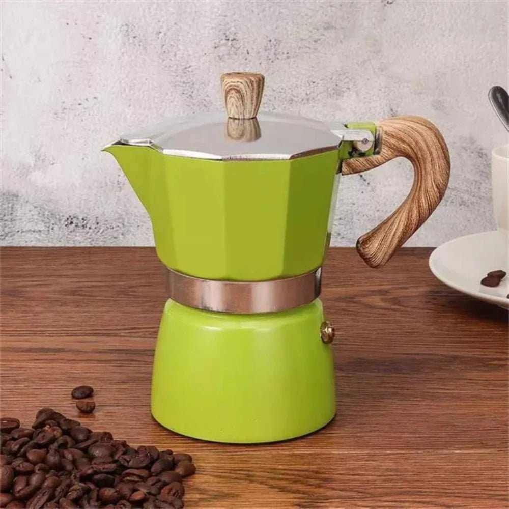 Green espresso maker with wooden handle on a wooden surface with coffee beans.