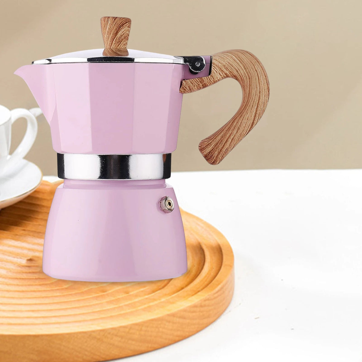 Pink espresso pot with wooden handle on a wooden coaster