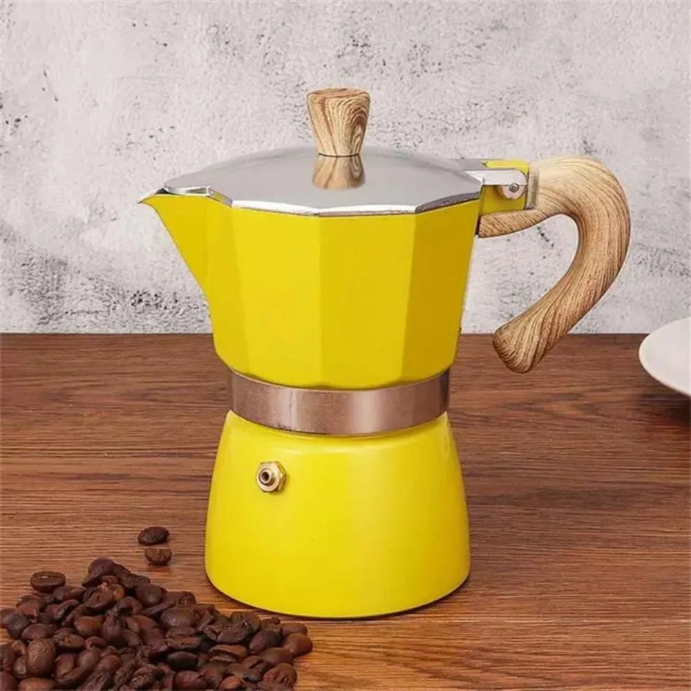Yellow stovetop espresso maker with wooden handle and base on a wooden surface with coffee beans.