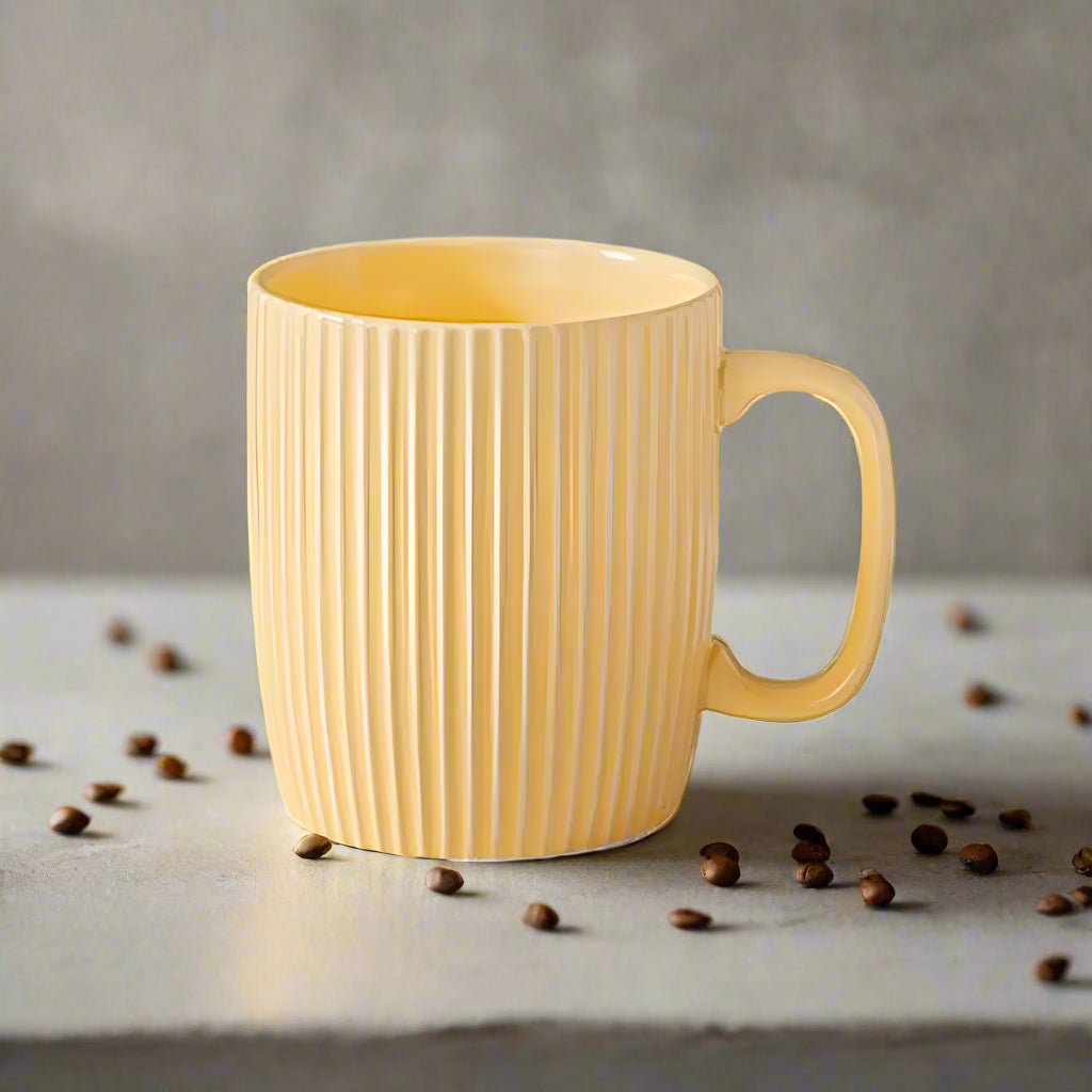 Yellow mug with ribbed texture on a surface with scattered coffee beans.