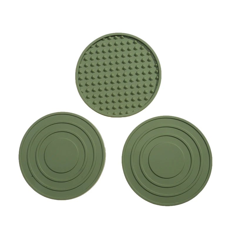 Three green silicone coasters with textured surface on a white background
