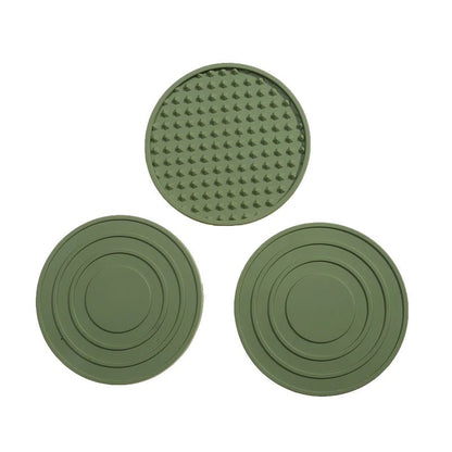 Three green silicone coasters with textured surface on a white background