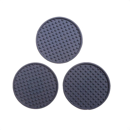 Three round, textured black coasters on a white background
