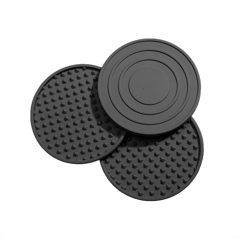 Three black circular silicone mats with textured surfaces on a white background