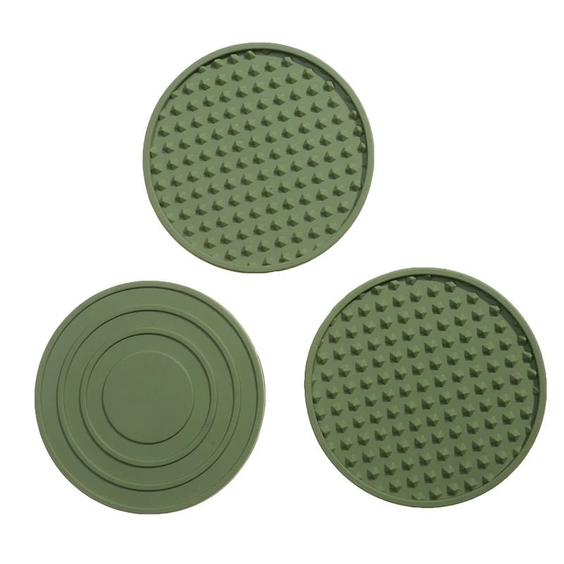 Three green round silicone coasters with textured surfaces on a white background