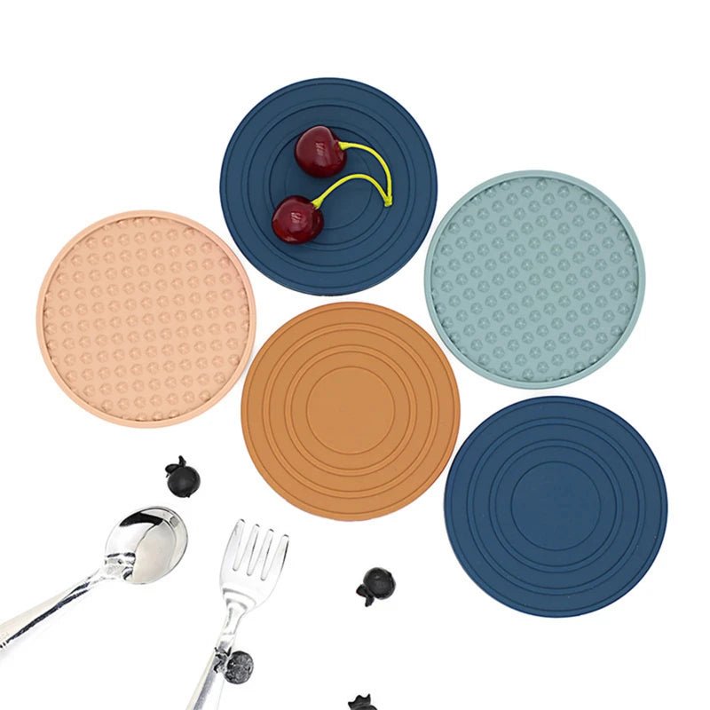 Set silicone coasters in various colors with utensils on a white background