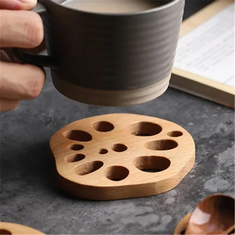 Wooden coaster with multiple holes on a dark surface, holding a cup.