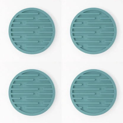 Four teal silicone coasters with textured surface on a white background