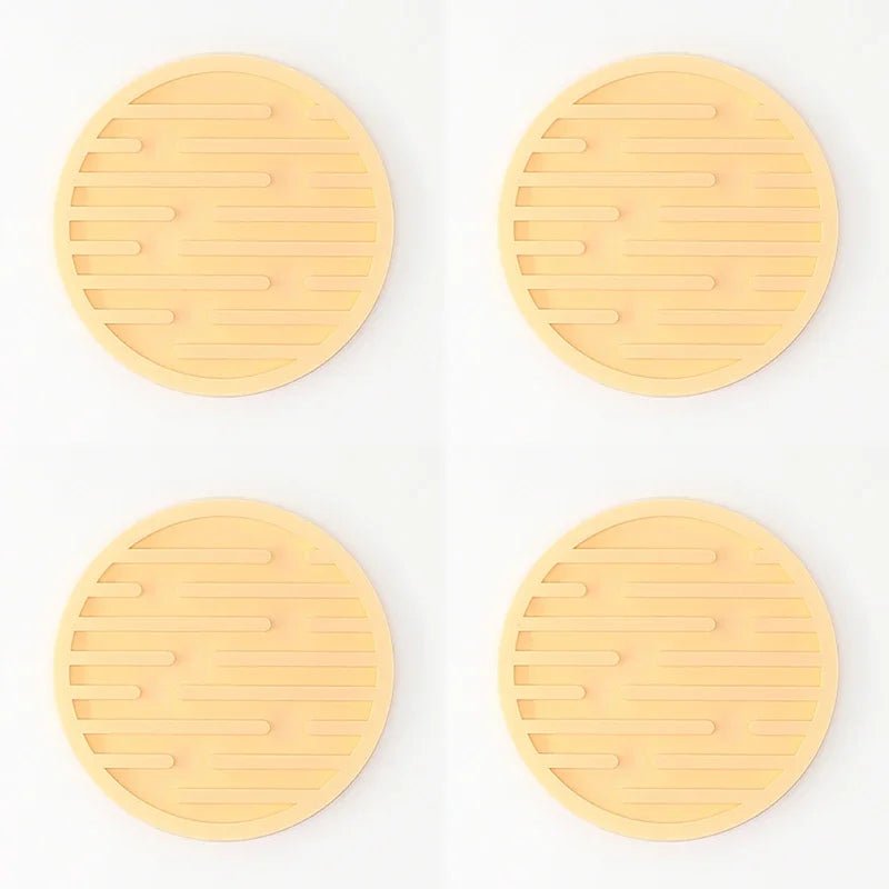 Four yellow silicone coasters with textured surface on a white background