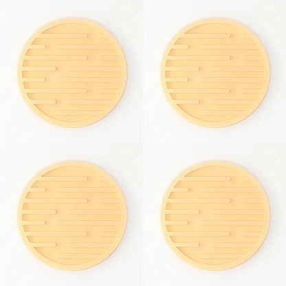 Four yellow silicone coasters with textured surface on a white background