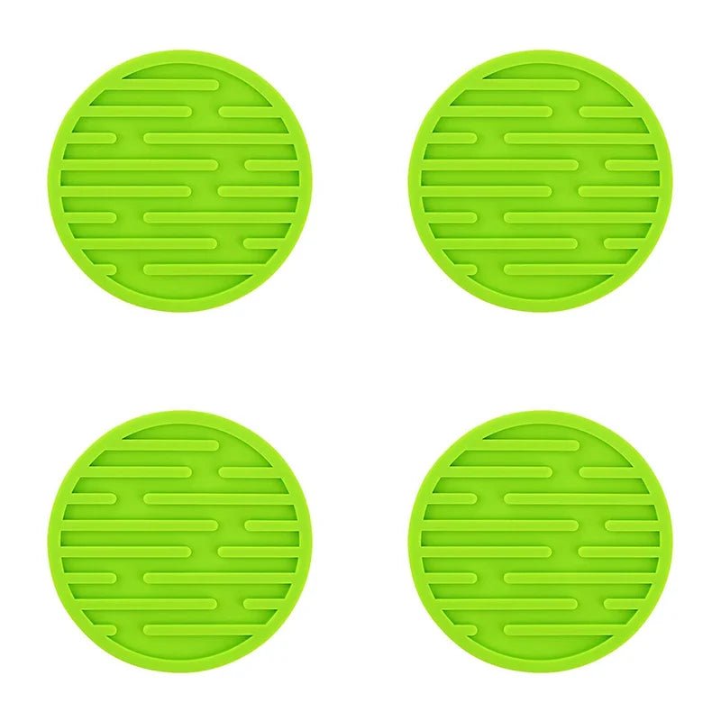 Four green silicone coasters with textured surface on a white background