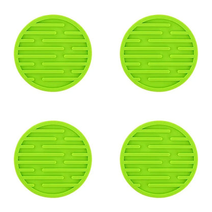 Four green silicone coasters with textured surface on a white background