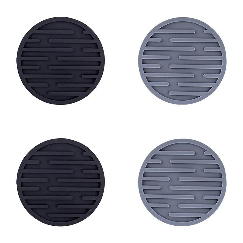 Four round silicone coasters in black and gray on a white background