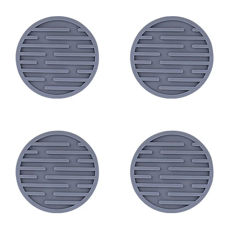 Four grey silicone coasters with textured surface on a white background