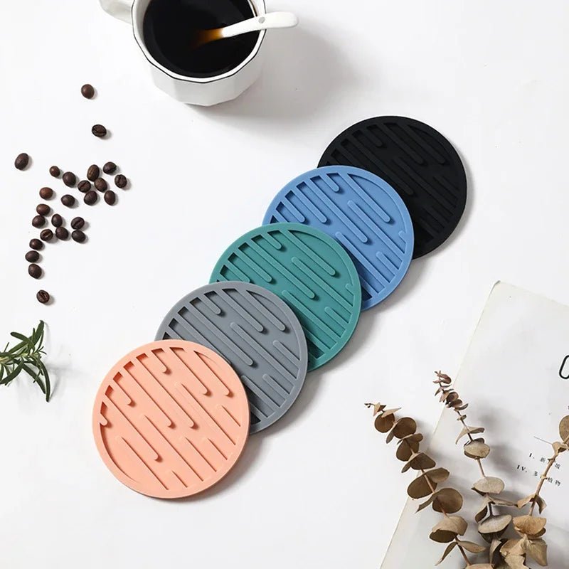 Set of colorful silicone coasters on a white surface with coffee and coffee beans.