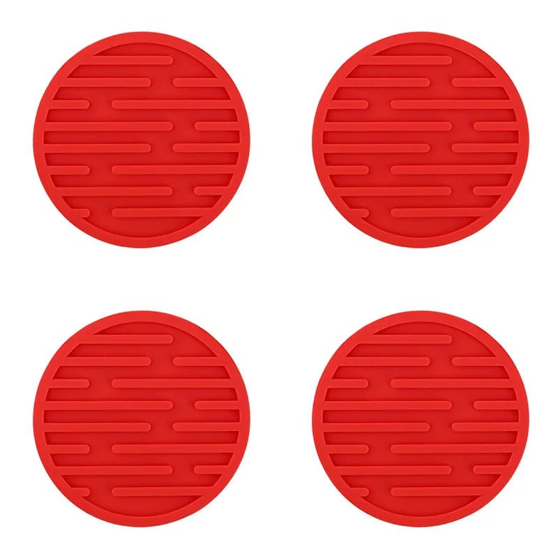 Four red silicone coasters with textured surface on a white background