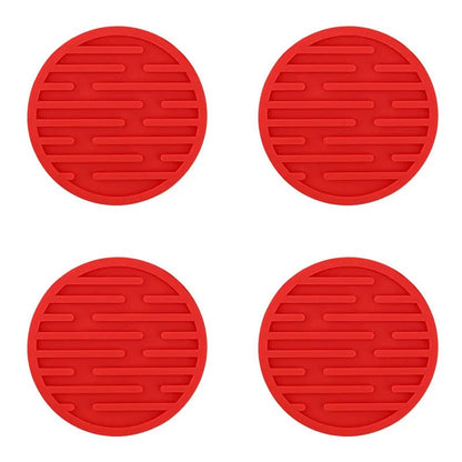 Four red silicone coasters with textured surface on a white background