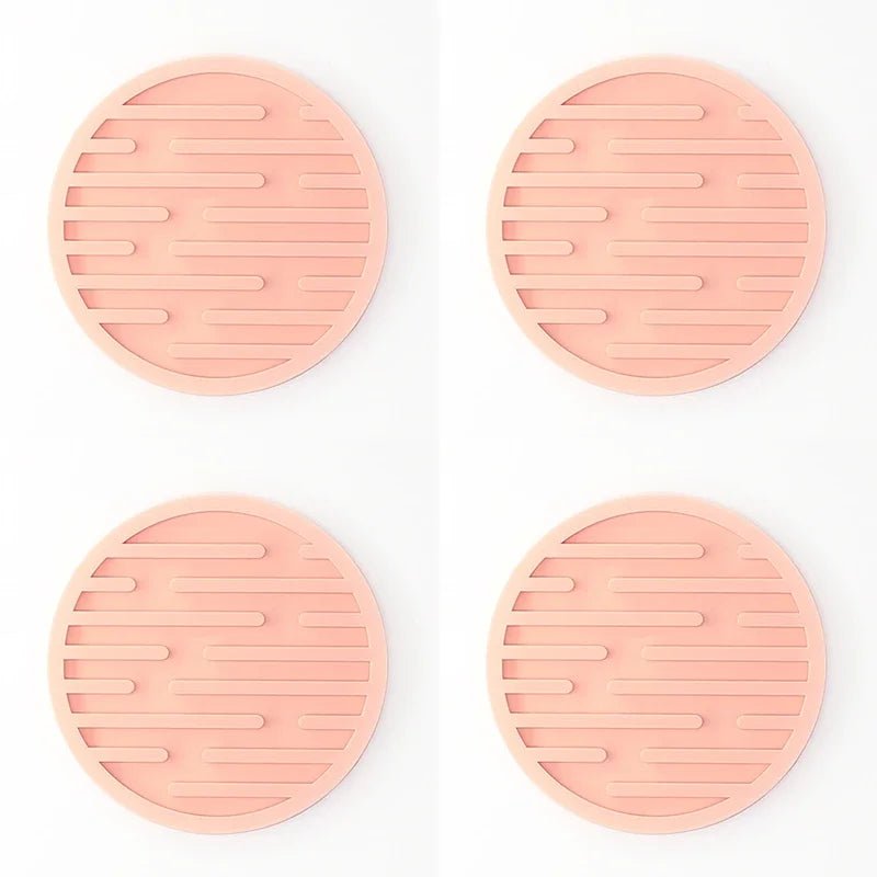 Four pink silicone coasters with textured surface on a white background