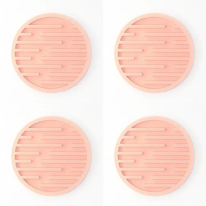 Four pink silicone coasters with textured surface on a white background
