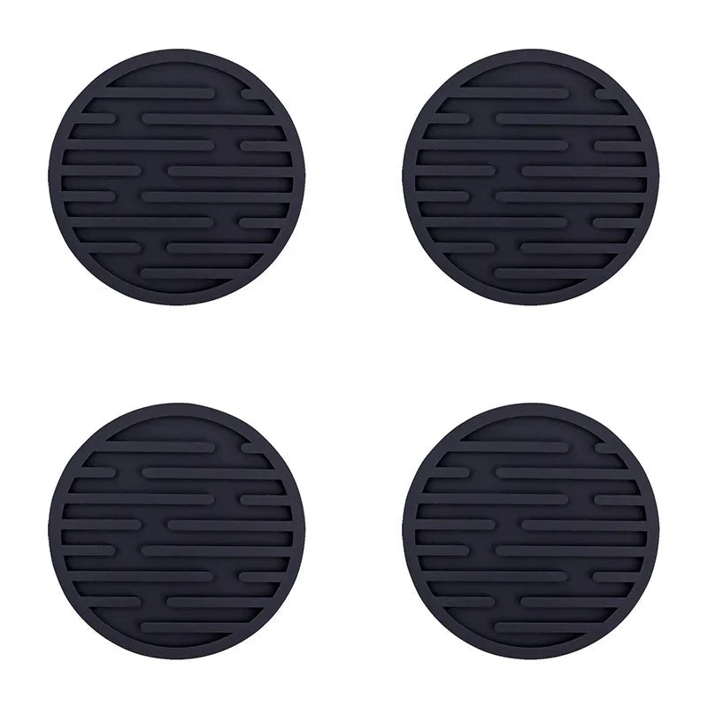 Four black silicone coasters with textured surface on a white background