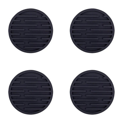 Four black silicone coasters with textured surface on a white background