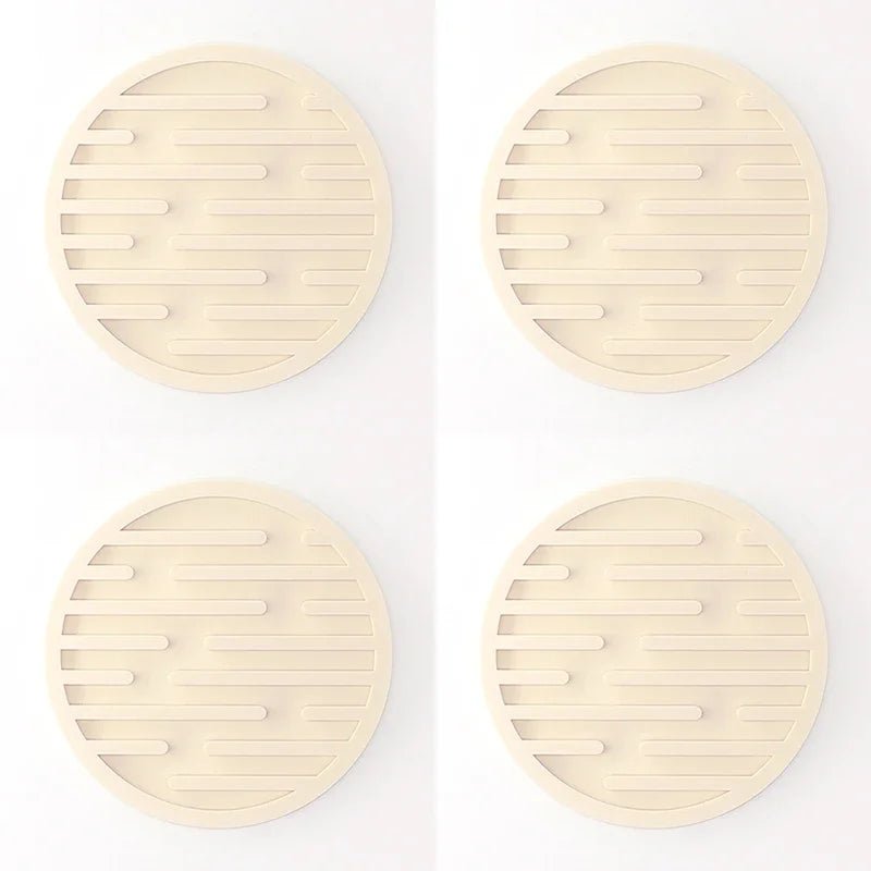 Four beige silicone coasters with textured surface on a white background