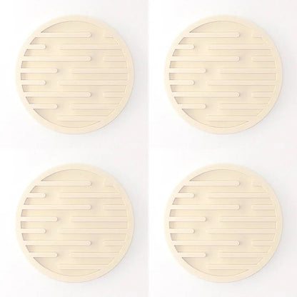 Four beige silicone coasters with textured surface on a white background