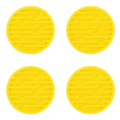 Four yellow silicone coasters with textured surface on a white background
