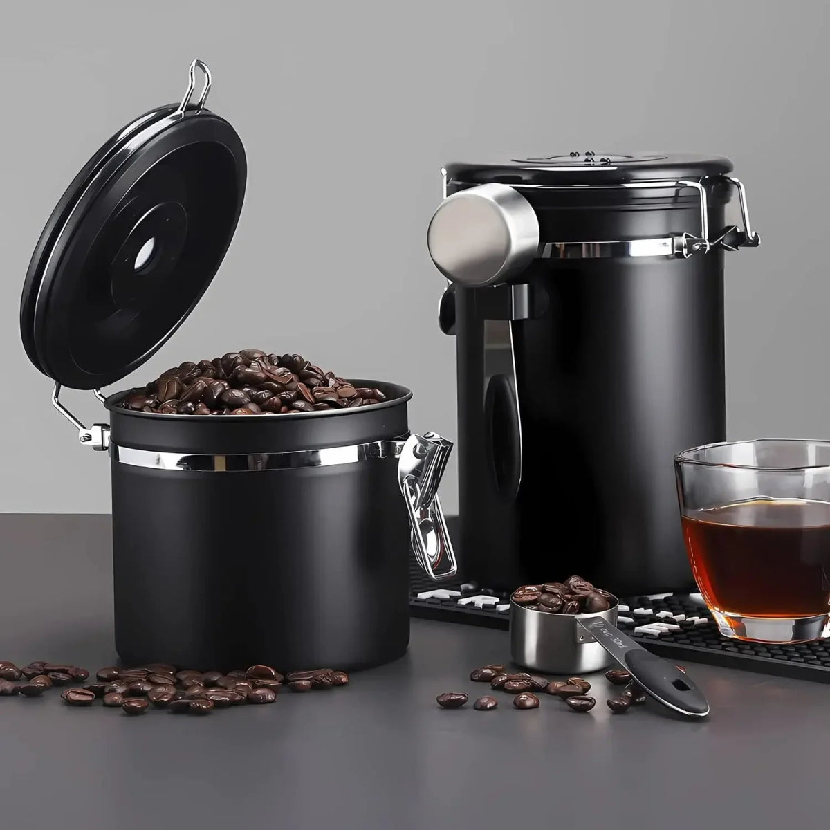 Black coffee canister with open lid, filled with coffee beans, on a gray background.