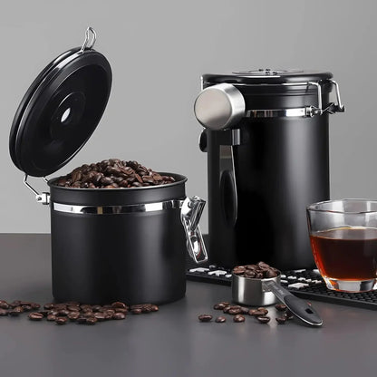 Black coffee canister with open lid, filled with coffee beans, on a gray background.
