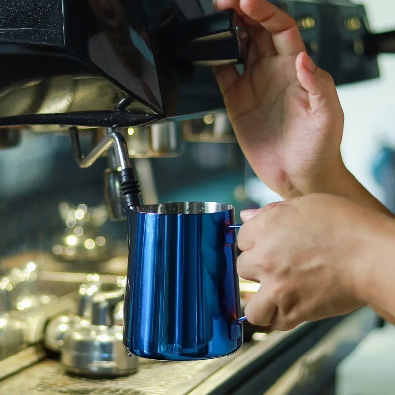 Person pouring coffee from a blue cup into an espresso machine.