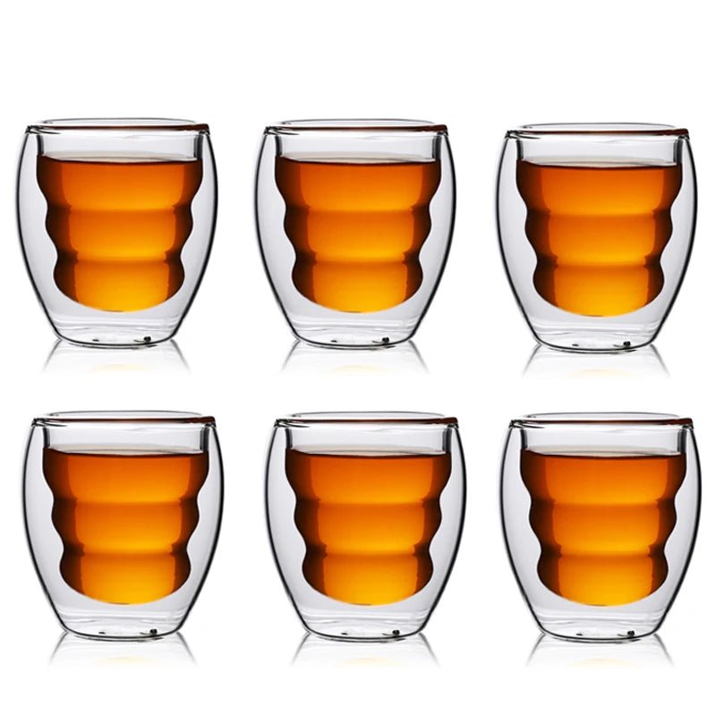 Set of six double-walled glass cups with a drink inside on a white background
