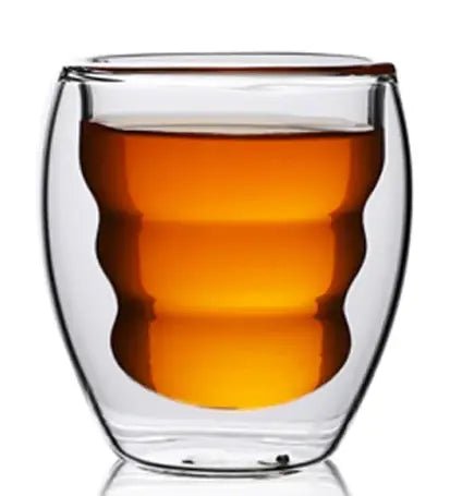 Clear glass coffee with a double-walled design filled with amber liquid on a white background