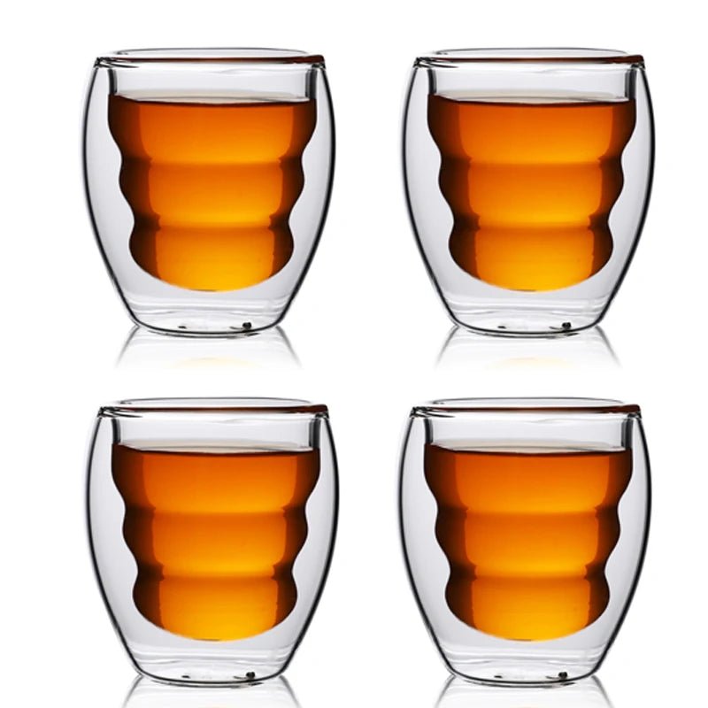 Four double-walled glass cups with a clear liquid on a white background