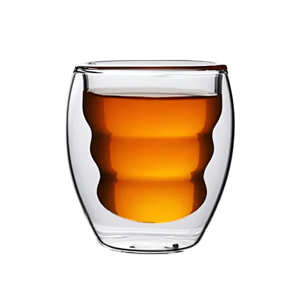 Clear glass coffee with a double-walled design filled with amber liquid on a white background