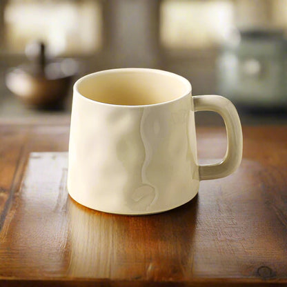 beige ceramic mug with embossed design on a wooden surface