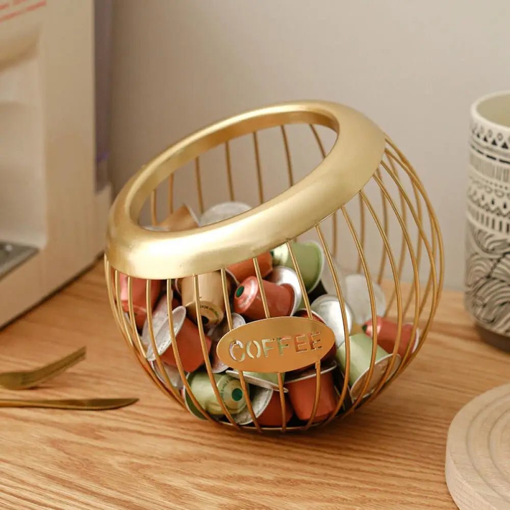 Gold wire basket filled with coffee pods on a wooden surface