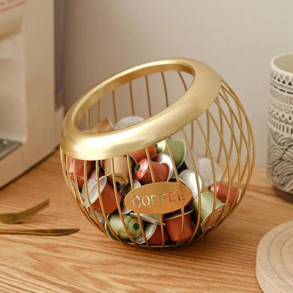 Gold wire basket filled with coffee pods on a wooden surface