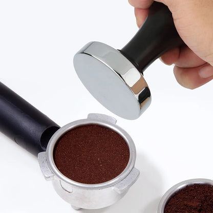 Hand using a coffee tamp to compress ground coffee in a portafilter on a white background